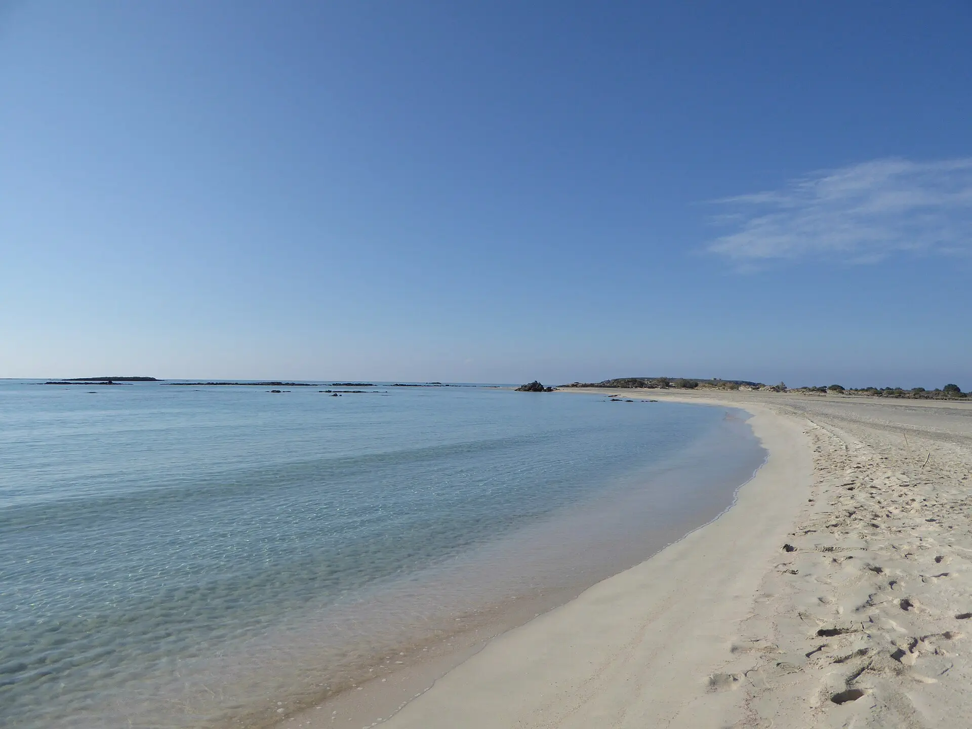 Heller Sandstrand und klares, flaches Wasser bei Elafonisi auf Kreta unter blauem Himmel, im Sand nur Fußspuren
