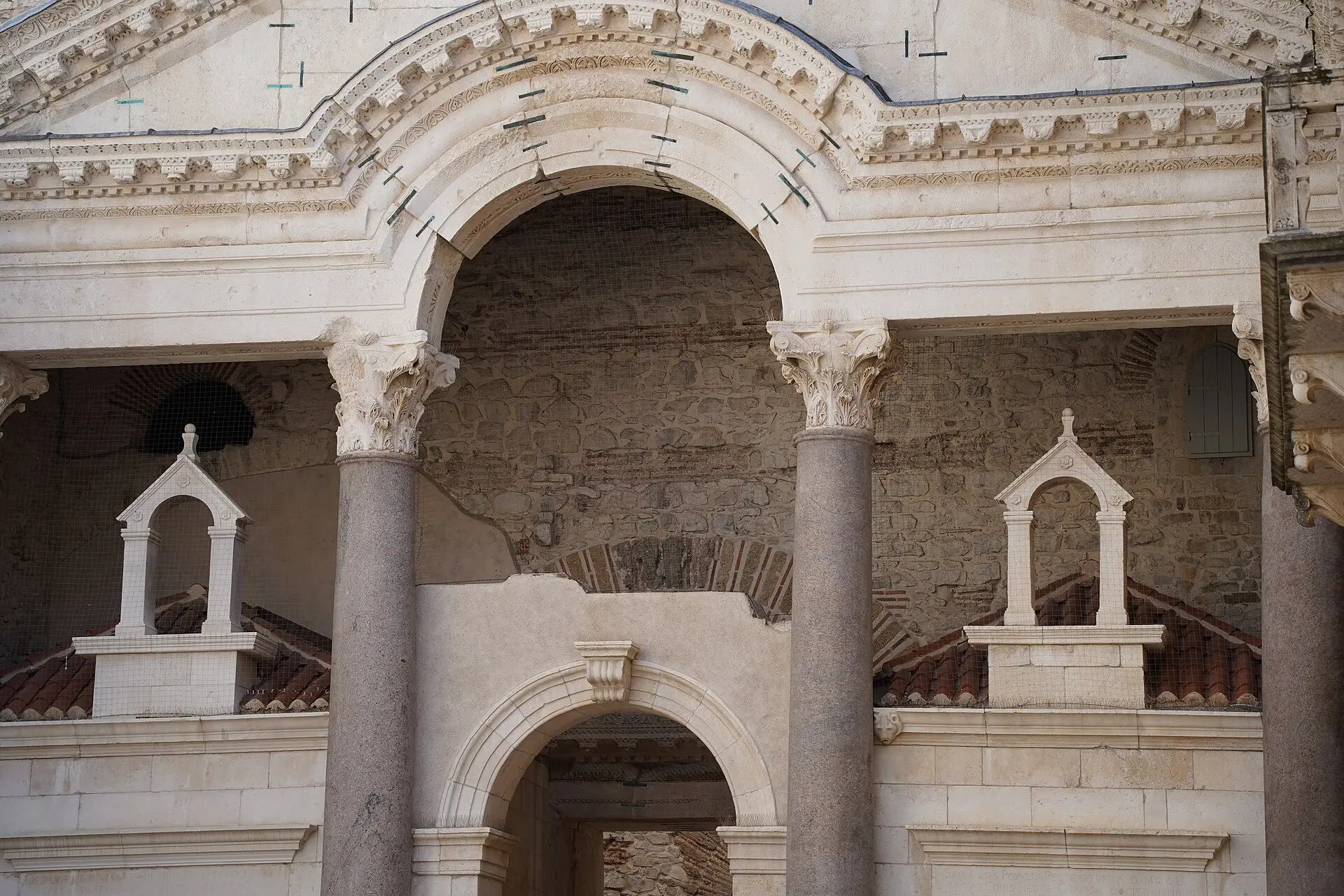Granitsäulen mit korinthischen Kapitellen und verziertem Rundbogen im Peristyl des Diokletianpalasts in Split