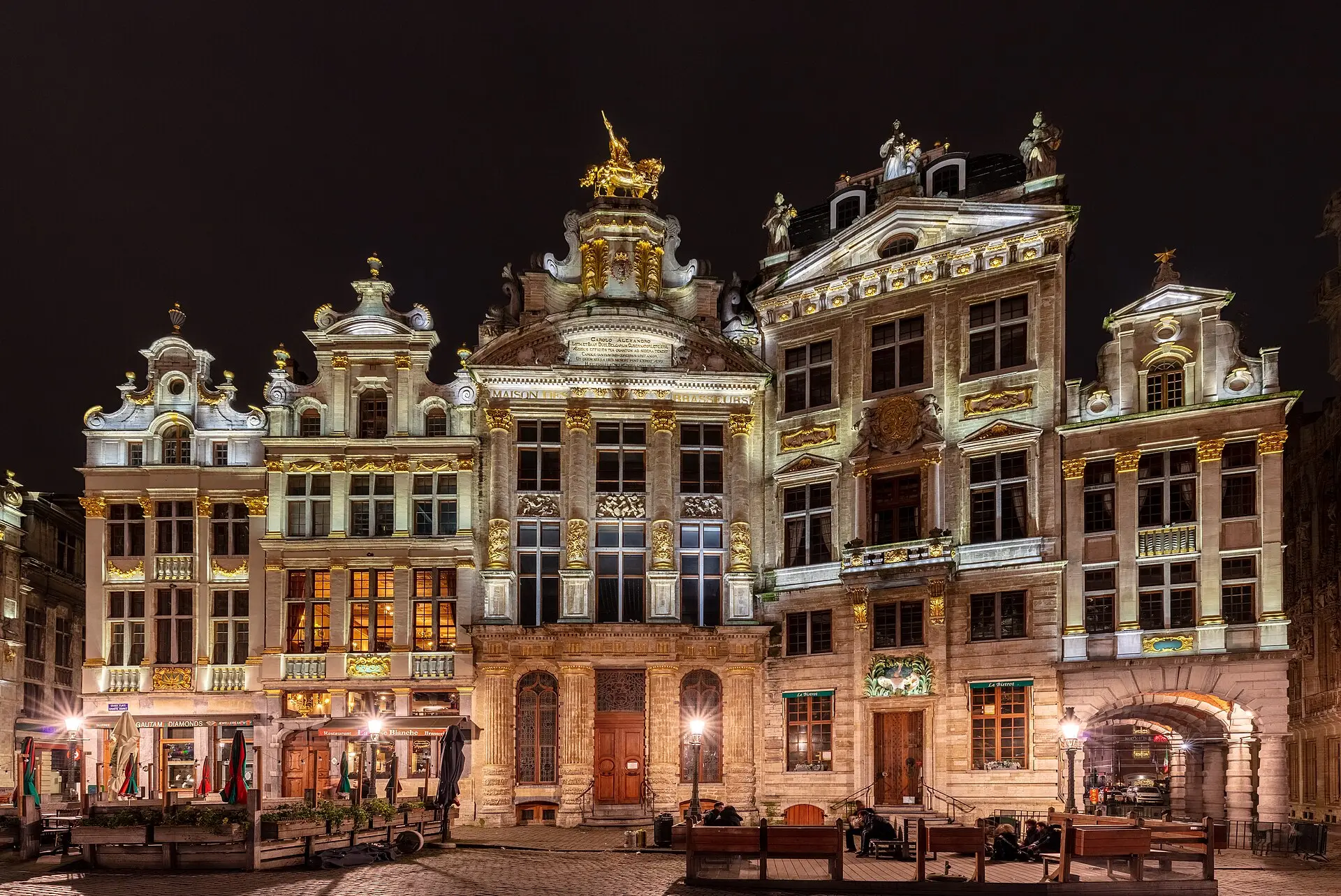 Angestrahlte Häuser an der Grand-Place in Brüssel bei Nacht, mit vergoldetem Schmuck und goldener Reiterfigur auf einem Giebel