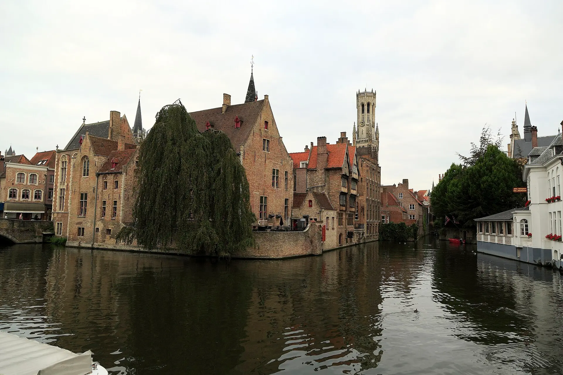 Kanal am Rozenhoedkaai in Brügge mit Backsteinhäusern, Treppengiebeln und Trauerweide, im Hintergrund der Belfried