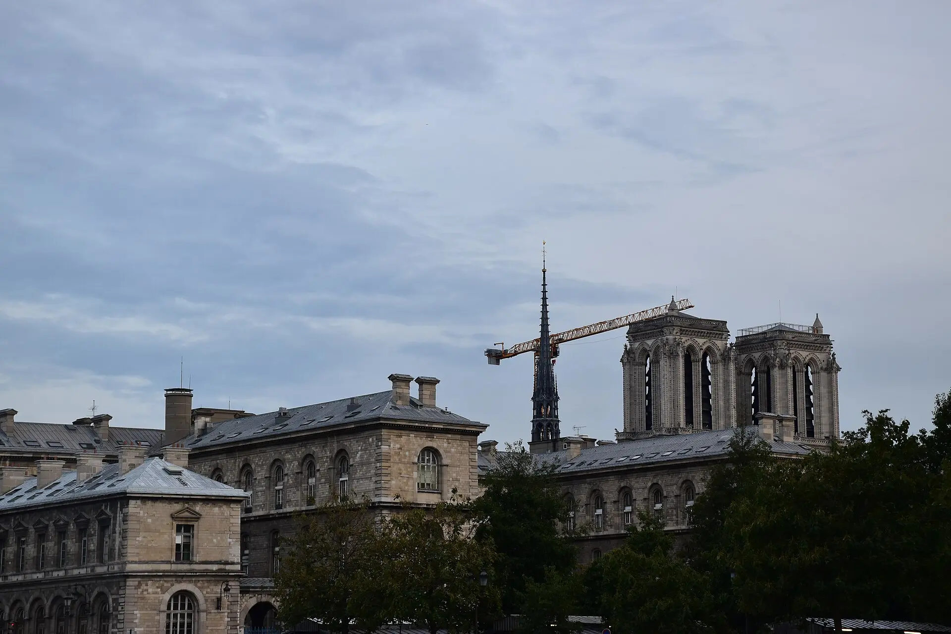Türme und neuer Vierungsturm von Notre-Dame über den Dächern der Île de la Cité im Oktober 2025, daneben ein Baukran