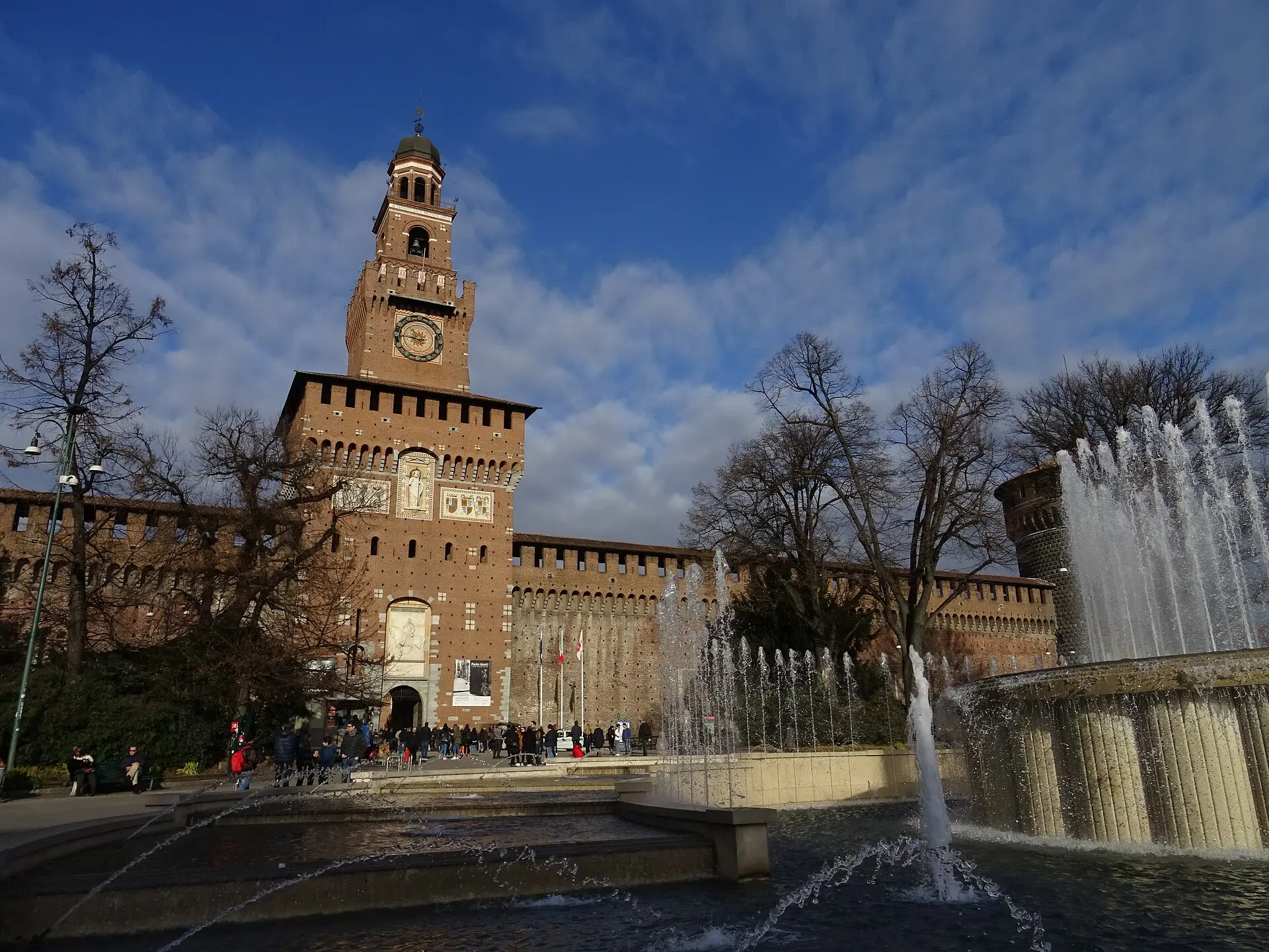 Torre del Filarete mit Uhr über dem Haupttor des Castello Sforzesco, davor Besucher, rechts der Brunnen mit Fontänen