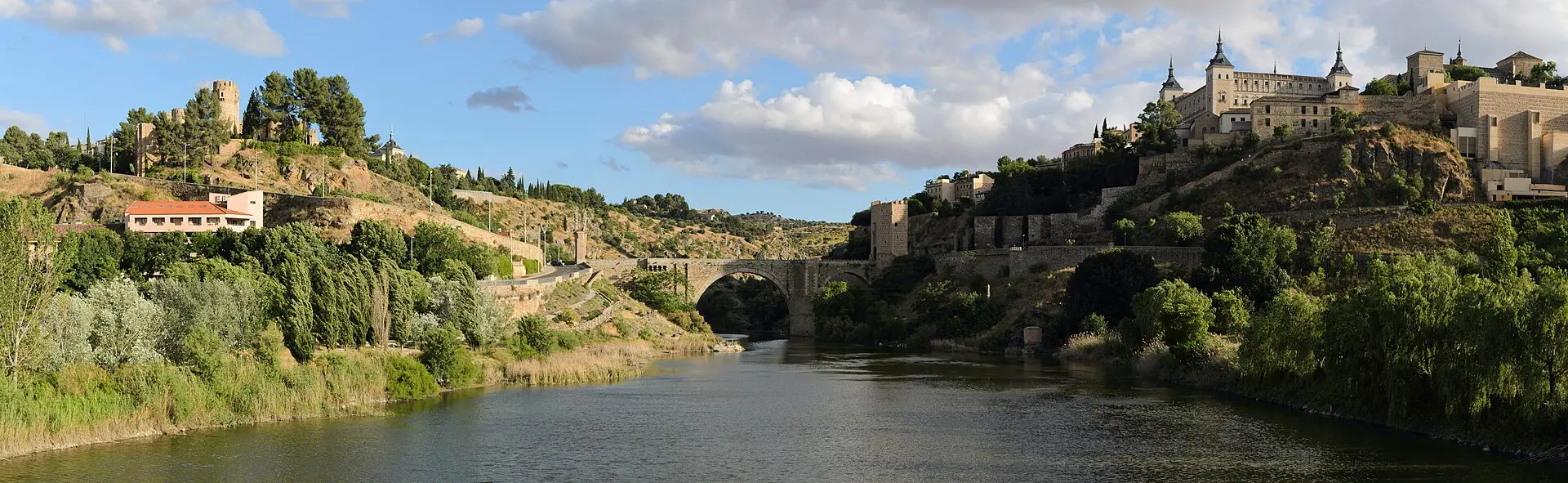 Toledo über dem Tajo: der Fluss im Vordergrund, in der Mitte die Puente de Alcántara, rechts oben der Alcázar, links eine Burganlage