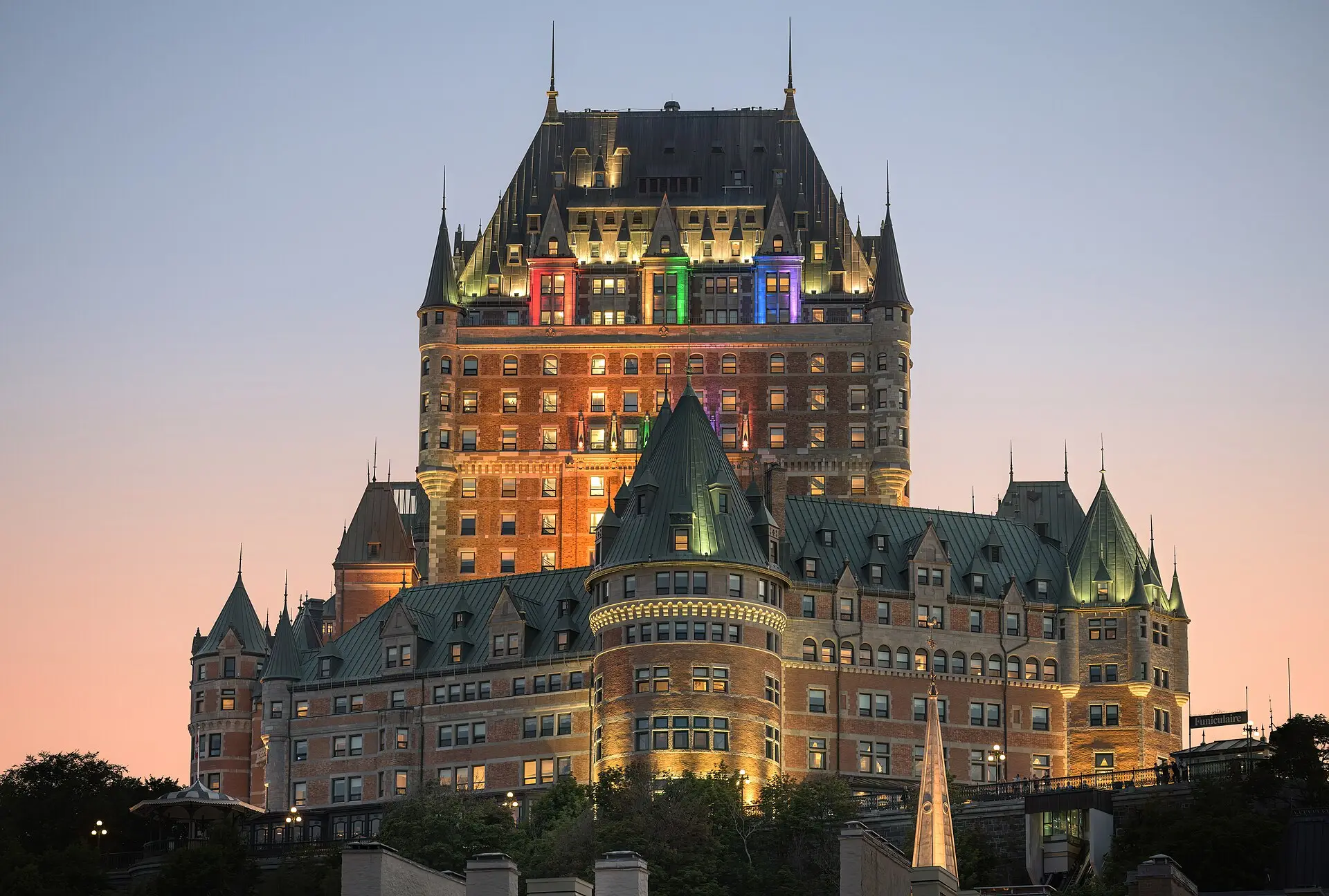Château Frontenac in Québec in der Abenddämmerung, beleuchtete Backsteinfassade mit grünen Kupferdächern und Türmchen
