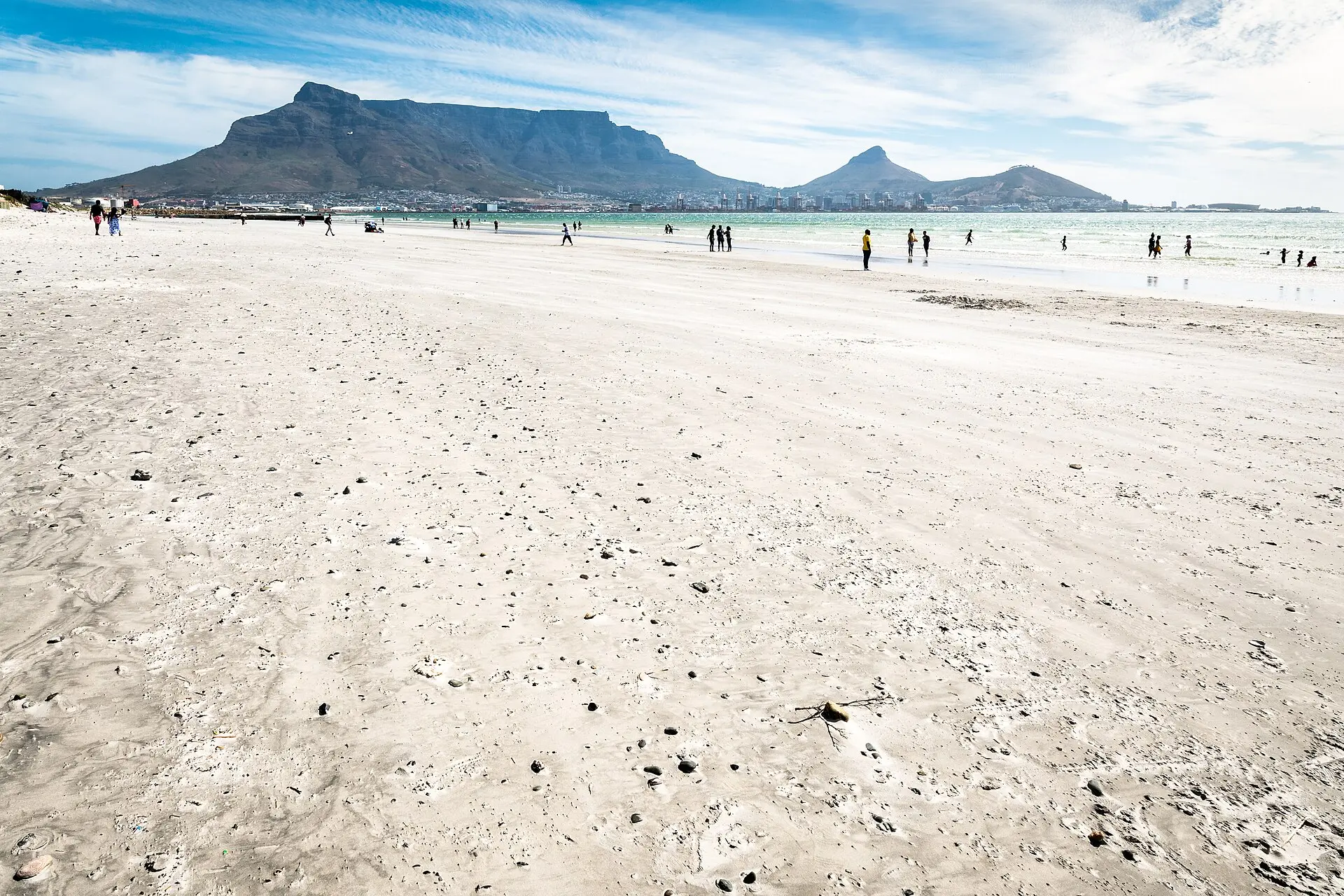 Breiter Sandstrand von Bloubergstrand, dahinter die Tafelbucht mit türkisem Wasser und der Tafelberg über dem Häuserstreifen von Kapstadt