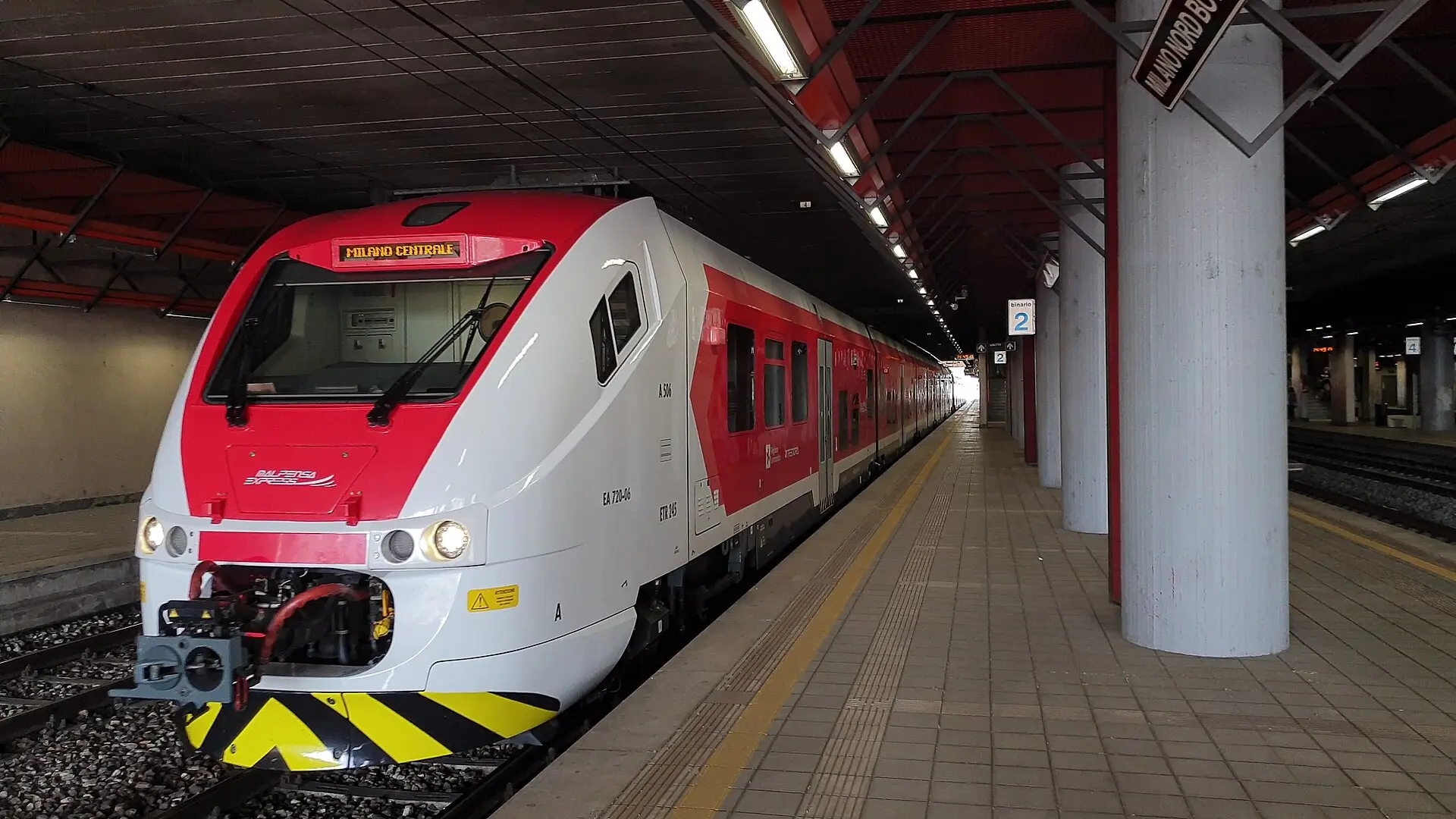 Rot-weißer Zug des Malpensa Express mit der Zielanzeige Milano Centrale am leeren Bahnsteig 2 im Bahnhof Milano Bovisa