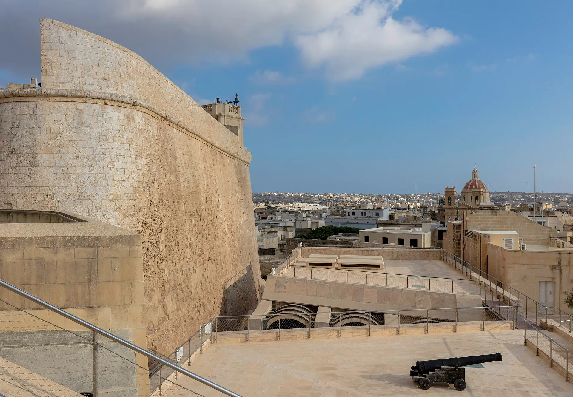 Cittadella von Victoria auf Gozo: geschwungene Festungsmauer aus hellem Kalkstein, dahinter die Dächer der Stadt und eine Kirchenkuppel