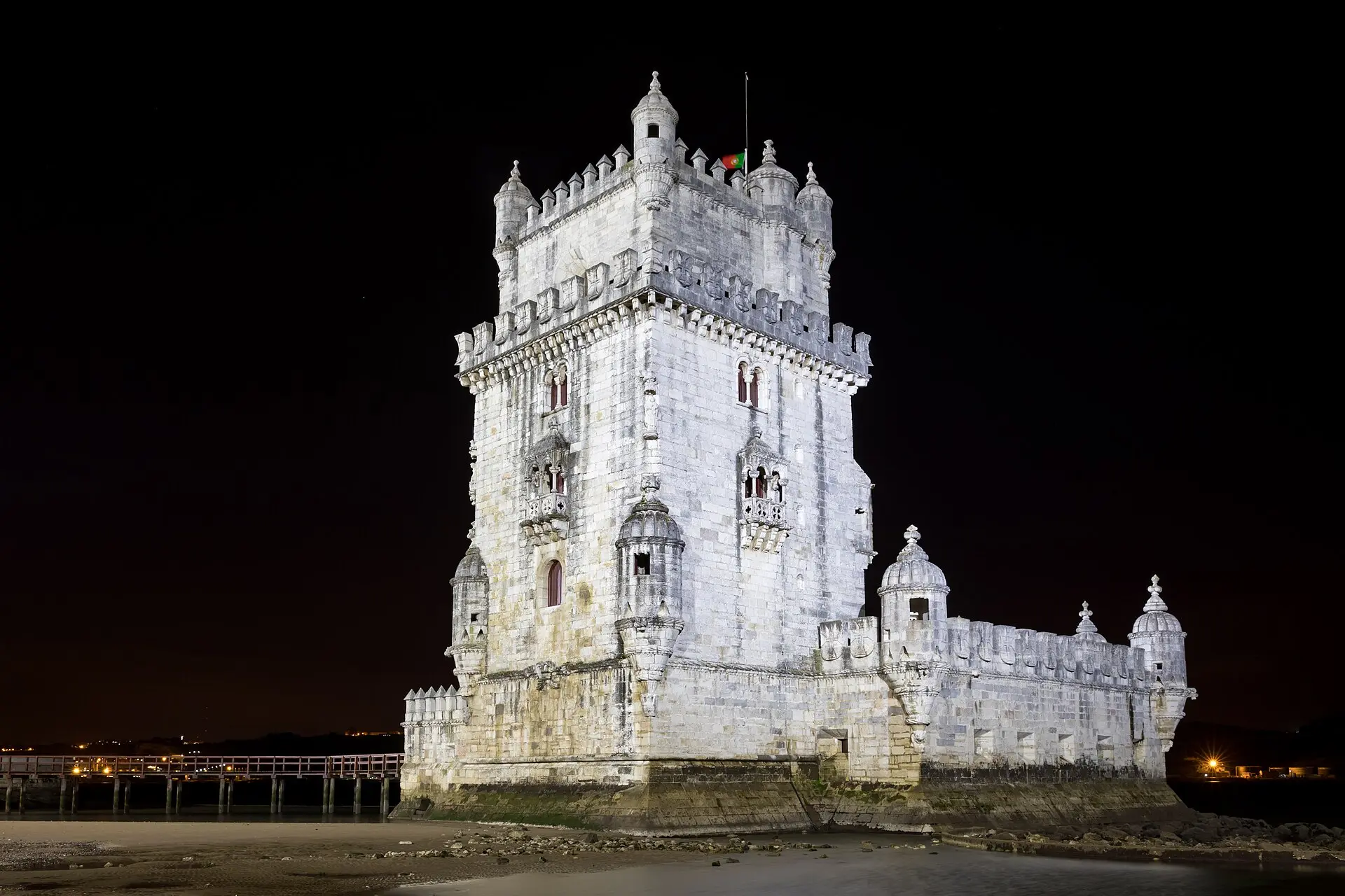 Die Torre de Belém in Lissabon bei Nacht, vom Ufer aus gesehen