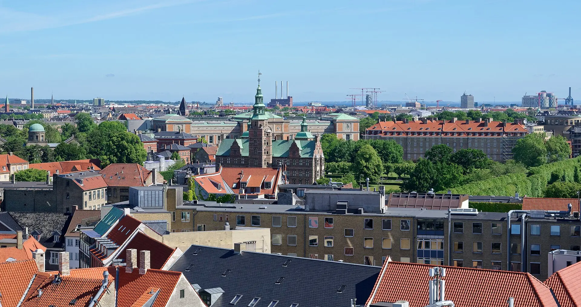 Blick vom Runden Turm über rote Dächer auf Schloss Rosenborg mit grünen Turmspitzen und die Bäume von Kongens Have