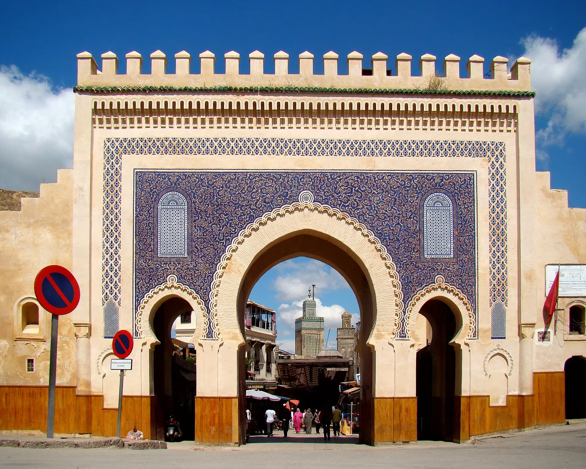 Stadttor Bab Boujloud in Fès mit blauen Kachelflächen, Zinnen und drei Bögen, durch den Mittelbogen sind Minarette zu sehen